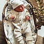 newborn, baby, infant, basket, blanket, hat, onesie, clothing, sleepwear, soft, plush, cozy, indoor, floor, wooden_floor, cute, portrait, child, small_hands, warm