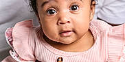 Nylah is registered to the contest to win money with this photo: baby, child, pink_bow, pink_clothing, curly_hair, droplet, hands, adult_hands, portrait, close_up, cute, expression, indoor, soft_lighting, face, eyes, infant, person, holding, adorable