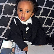 Kaylan participe au concours pour gagner de l'argent avec cette photo : baby_bottle, black_clothing, bow_tie, child, couch, curiosity, curly_hair, expression, furniture, indoor, keyboard, patterned_fabric, screen, sitting, small_person, tablet, technology, toddler, touchscreen, white_shirt