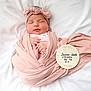 baby, baby_clothes, birth_announcement, blanket, cute, headband, infant, lying_down, newborn, newborn_photo, peaceful, pink, plush, portrait, resting, sleeping, soft, white, wooden_plaque, wrapped