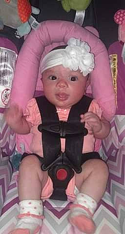 Aurora is registered to the contest to win money with this photo: arm, baby, baby_toddler_clothing, cheek, child, doll, event, eye, finger, headwear, human_body, human_leg, lap, leg, person, pink, purple, skin, thigh, thumb