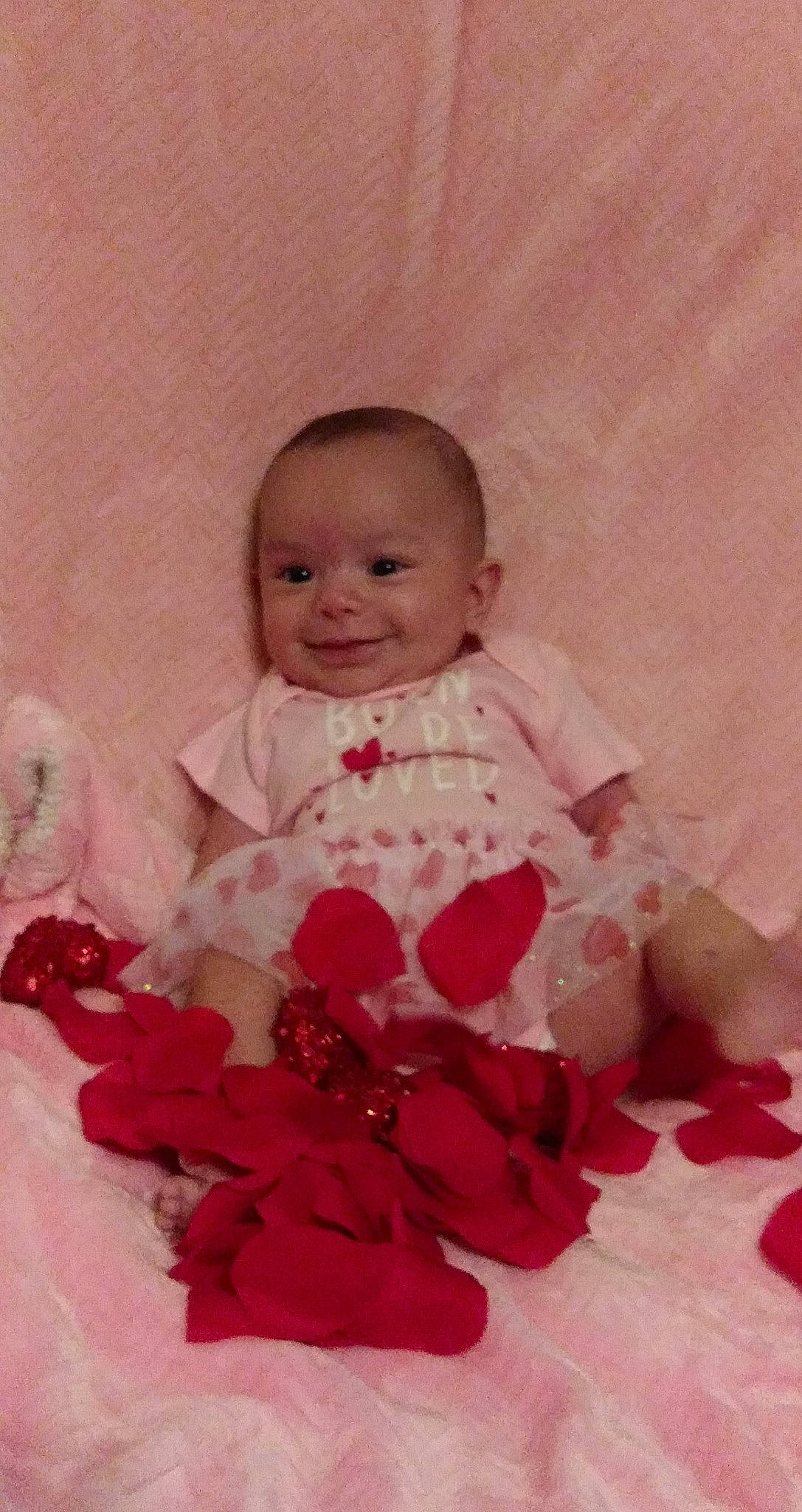 Aurora is registered to the contest to win money with this photo: baby, baby_toddler_clothing, cheek, dress, embellishment, face, happy, head, headgear, headpiece, iris, joy, magenta, outerwear, person, petal, pink, ruffle, skin, sleeve