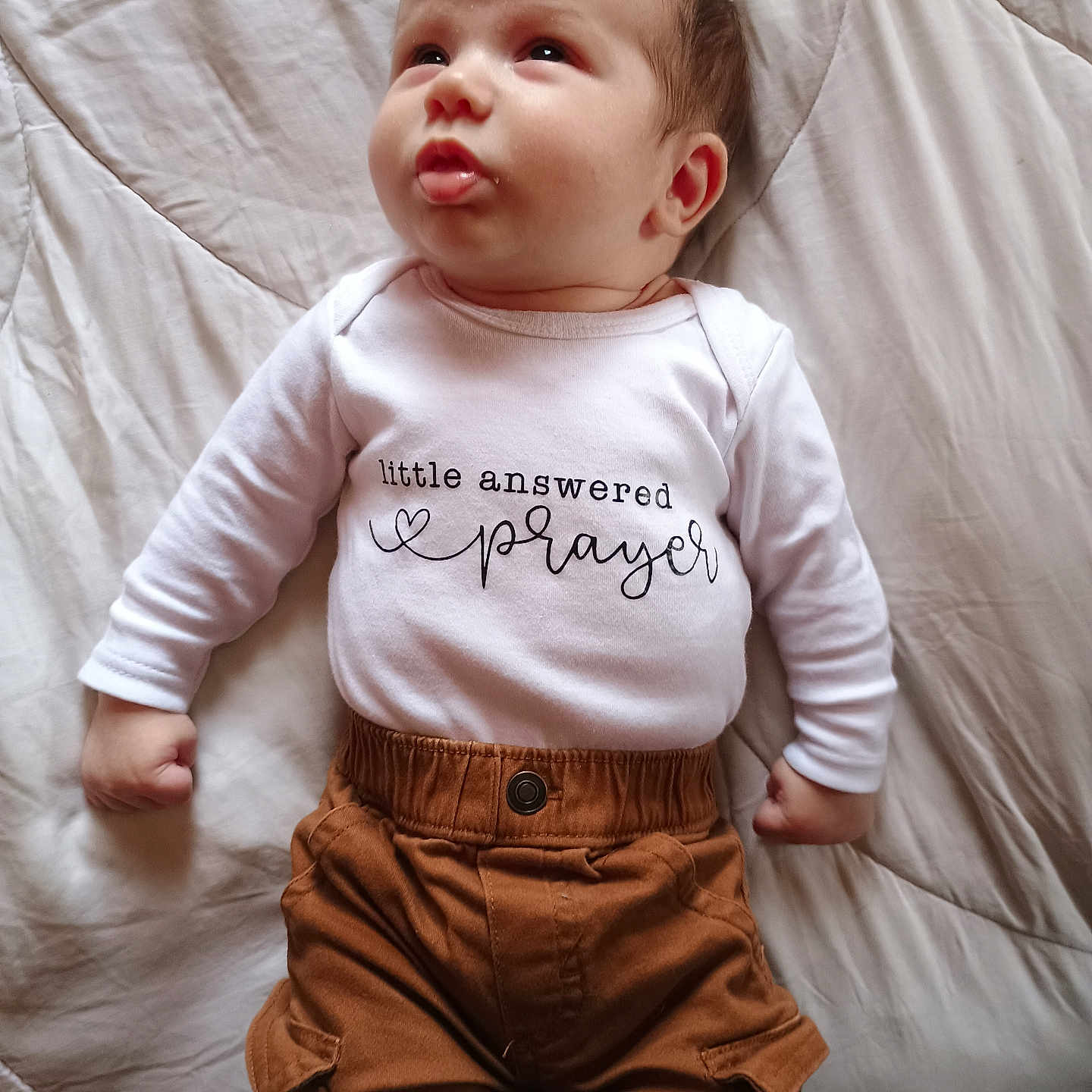 Jason joined the competition — help win amazing prizes! baby, infant, child, white_shirt, brown_pants, lying_down, blanket, cute, expression, face, hands, clothing, soft_light, indoors, portrait, young_child, skin, head, eyes, mouth