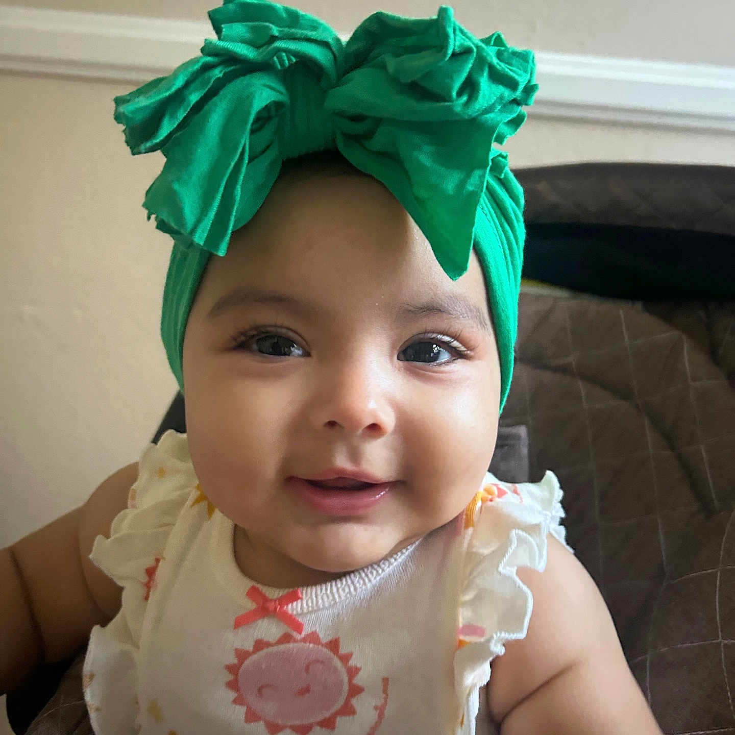 Aliany is registered to the contest to win money with this photo: accessory, apparel, baby, child, closeup, clothing, cute, expression, face, fashion, green_bow, happy, headband, indoor, infant, person, portrait, sitting, smiling, young_child
