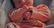 Tracie is registered to the contest to win money with this photo: baby, newborn, infant, sleeping, smiling, onesie, orange_clothing, blanket, cushion, baby_seat, indoors, cozy, cute, child, face, peaceful, soft_texture, resting, portrait, young