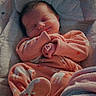 baby, newborn, infant, sleeping, smiling, onesie, orange_clothing, blanket, cushion, baby_seat, indoors, cozy, cute, child, face, peaceful, soft_texture, resting, portrait, young