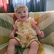Tracie joined the competition — help win amazing prizes! baby, smiling, sitting, indoor, headband, romper, blanket, couch, pattern, window, curtains, happy, child, person, clothing, infant, cute, portrait, home, cozy