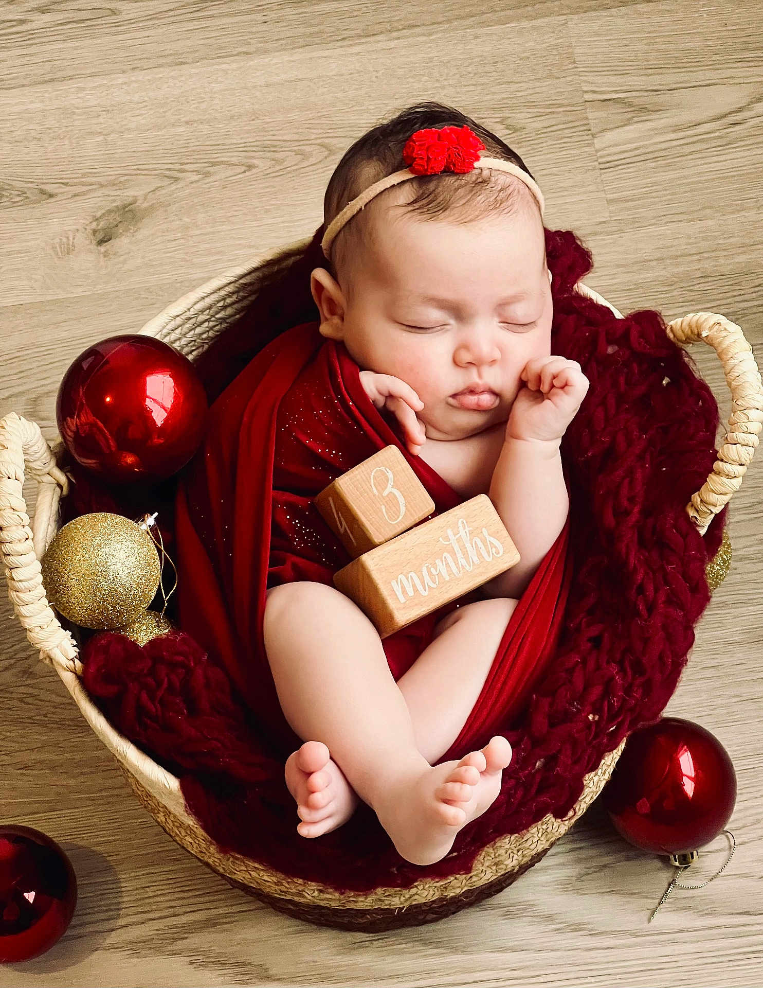 Baya participe au concours pour gagner de l'argent avec cette photo : baby, sleeping, basket, red_blanket, wooden_blocks, ornaments, red_ornaments, gold_ornaments, headband, flower_headband, infant, feet, hands, cute, cozy, holiday_theme, floor, wrapped, peaceful, portrait