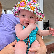 Abbigale joined the competition — help win amazing prizes! adult, baby, child, colorful, cute, face, floral, hand, happy, hat, holding, infant, outdoor, person, playful, porch, skin, smile, summer, swimsuit