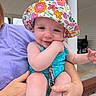 adult, baby, child, colorful, cute, face, floral, hand, happy, hat, holding, infant, outdoor, person, playful, porch, skin, smile, summer, swimsuit