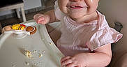 Abbigale is registered to the contest to win money with this photo: baby, child, crumbs, cute, expression, face, feeding, food, funny, happy, high_chair, indoor, infant, messy, person, pink_clothing, seat, smiling, table, toy