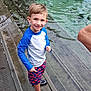 child, boy, water, pool, steps, swimwear, rash_guard, shorts, water_shoes, smiling, outdoor, swimming, person, adult, woman, nature, wood, reflection, summer, recreation