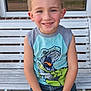 child, boy, smiling, bench, outdoor, dinosaur_tshirt, blue_eyes, short_hair, casual_clothing, summer, happy, portrait, sitting, concrete, window, reflection, trees, daylight, jeans_shorts, hands