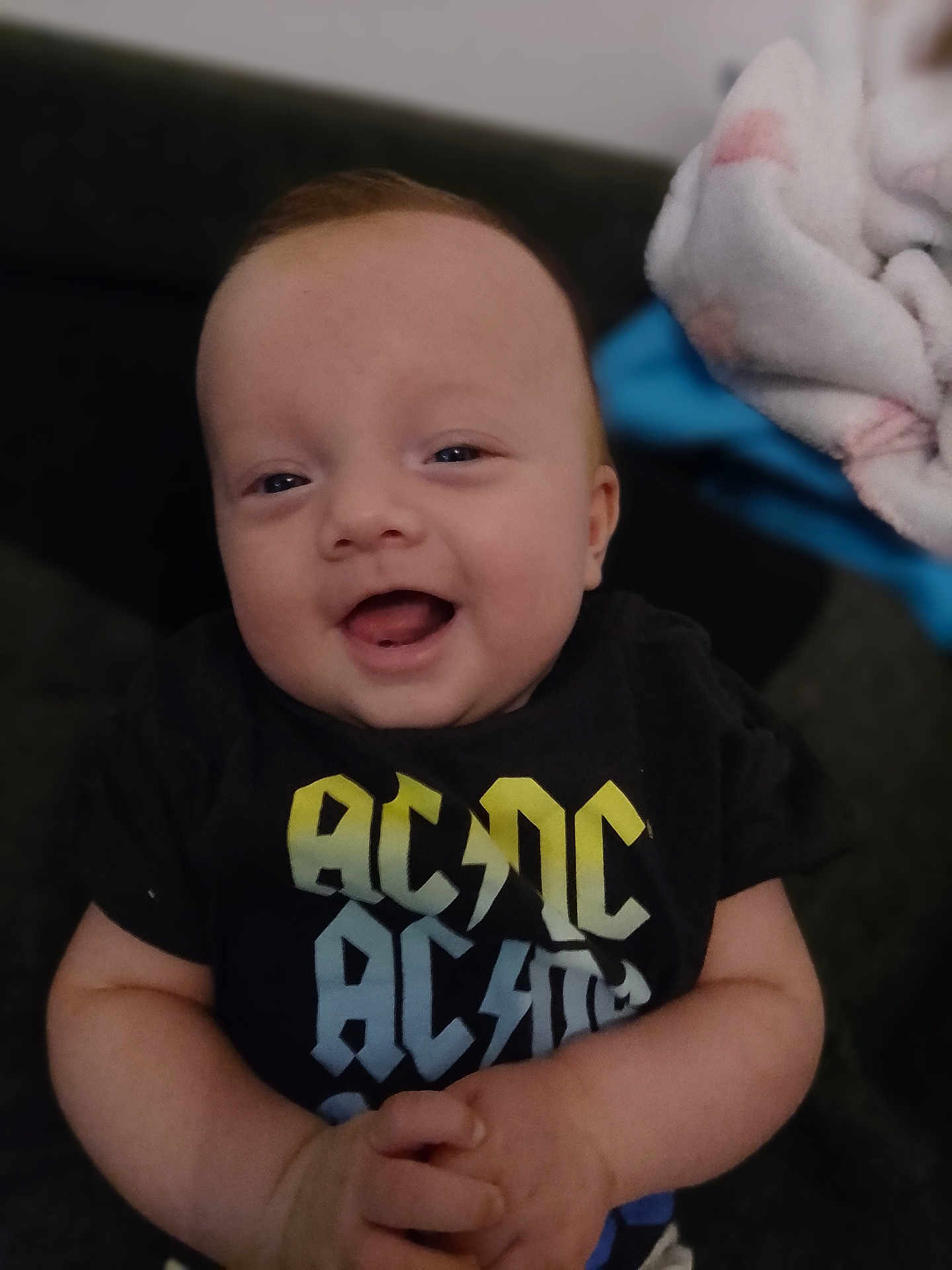 Gabriel a rejoint le concours — aidez-le/la à gagner de superbes lots ! baby, smiling, toddler, clothing, acdc, hands, happy, portrait, indoor, infant, cute, young_child, face, sitting, casual, short_sleeve, person, relaxed, blanket, cozy