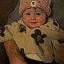 baby, child, hat, bear_hat, fleece_jacket, floral_pattern, smile, cute, infant, person, portrait, warm_clothing, indoor, adult_arm, hand, cozy, seated, face, looking_at_camera, happy