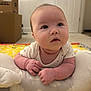 baby, infant, child, cushion, face, indoors, carpet, cardboard_box, curious, expression, hands, play_mat, soft_toy, tummy_time, white_clothing, room, window_blinds, floor, skin, head