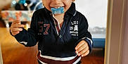 Illyann a rejoint le concours — aidez-le/la à gagner de superbes lots ! baby, child, clothing, cute, flooring, happy, hat, home, indoor, navy_shirt, pacifier, person, playful, portrait, shorts, smiling, toddler, walking, wooden_floor, young_child
