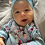 baby, blanket, blue, child, clothing, cozy, cushion, cute, face, floral_clothing, hands, happy, headband, indoors, infant, person, portrait, skin, smiling, young