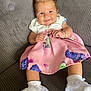 Romi-Dalton joined the competition — help win amazing prizes! baby, child, smiling, pink_dress, white_socks, lace, bow, hair_accessory, couch, sofa, indoor, portrait, happy, cute, infant, person, clothing, seated, furniture, skin