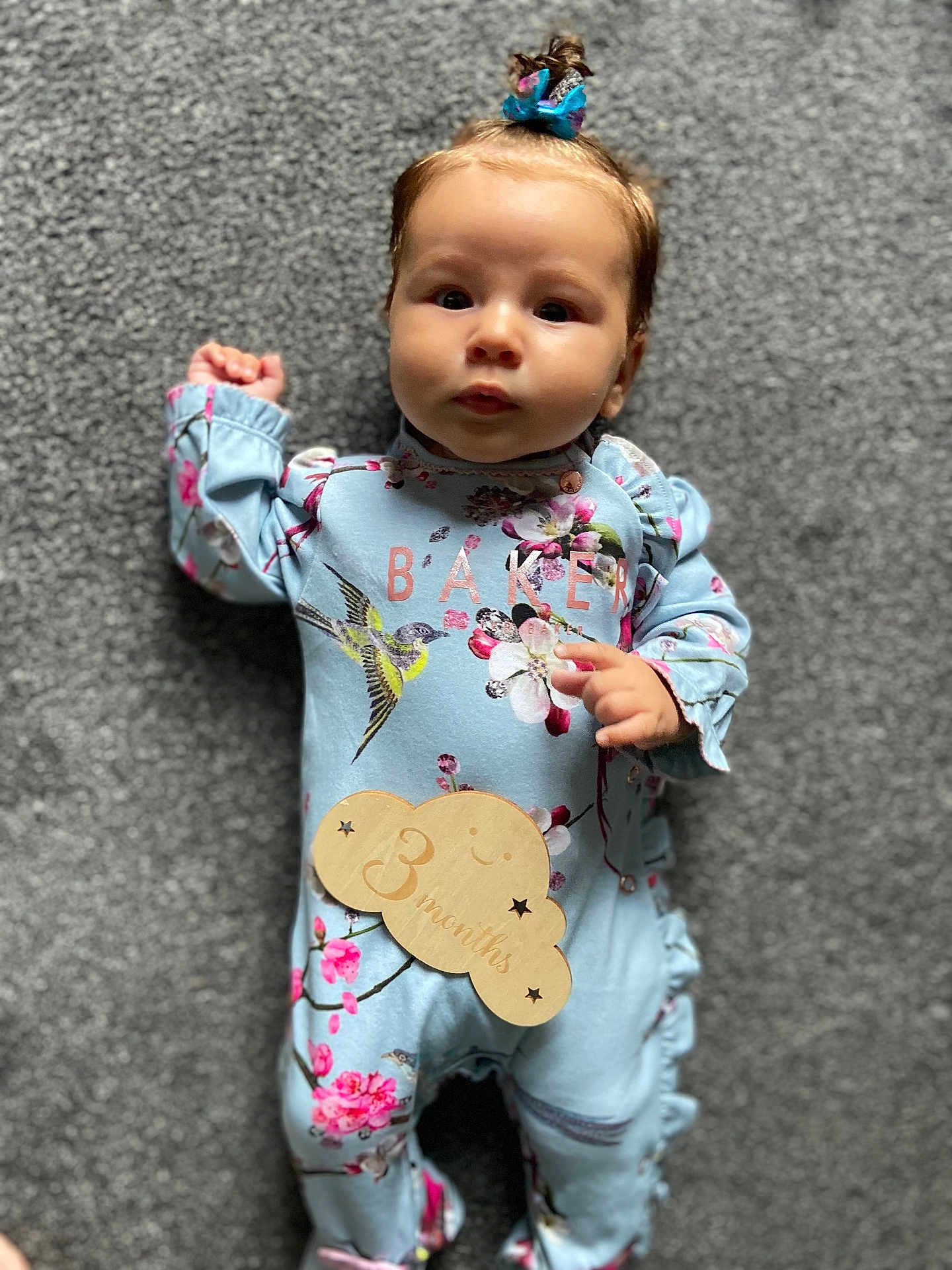 Romi-Dalton joined the competition — help win amazing prizes! baby, infant, child, onesie, blue_clothing, floral_pattern, bird_design, wooden_sign, 3_months, hair_bow, curious_expression, lying_down, carpet, soft_texture, cute, adorable, small_hands, indoor, portrait, closeup