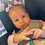 baby, child, car_seat, pink_bows, hand, blanket, sea_creatures, clothing, face, expression, safety_harness, indoor, cute, infant, person, closeup, adorable, seat, comfort, curious
