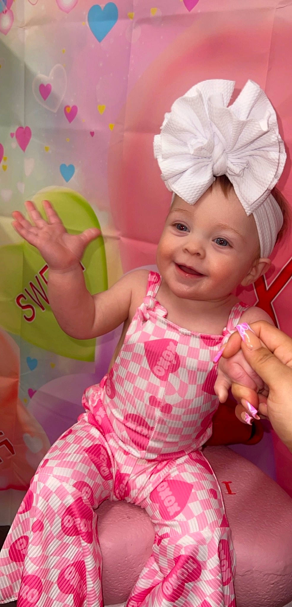 Raelynn is registered to the contest to win money with this photo: baby, baby_toddler_clothing, cheek, child, facial_expression, fashion_accessory, foot, fun, gesture, happy, headpiece, headwear, joy, magenta, peach, person, pink, play, skin, sleeve