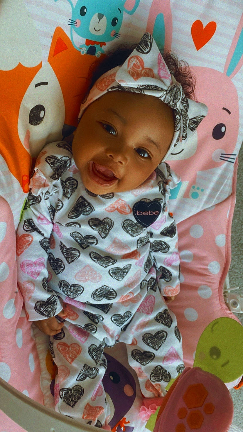 Khloé Chanel is registered to the contest to win money with this photo: baby, baby_toddler_clothing, cheek, child, eyelash, facial_expression, fun, happy, head, headwear, linens, lip, nose, pattern, person, pink, skin, sleeve, smile, t_shirt