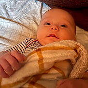 Paisley is registered to the contest to win money with this photo: baby, blanket, child, comfort, cozy, curious, cushion, cute, fabric, face, hand, indoor, infant, newborn, portrait, resting, soft_texture, striped_clothing, textile, warm