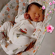 Luna is registered to the contest to win money with this photo: baby, newborn, sleeping, onesie, santa_claus, baby_seat, floral_pattern, hand, face, infant, cute, indoors, cozy, pink_flowers, child, peaceful, soft_lighting, holiday_theme, resting, portrait