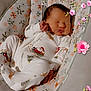 baby, newborn, sleeping, onesie, santa_claus, baby_seat, floral_pattern, hand, face, infant, cute, indoors, cozy, pink_flowers, child, peaceful, soft_lighting, holiday_theme, resting, portrait