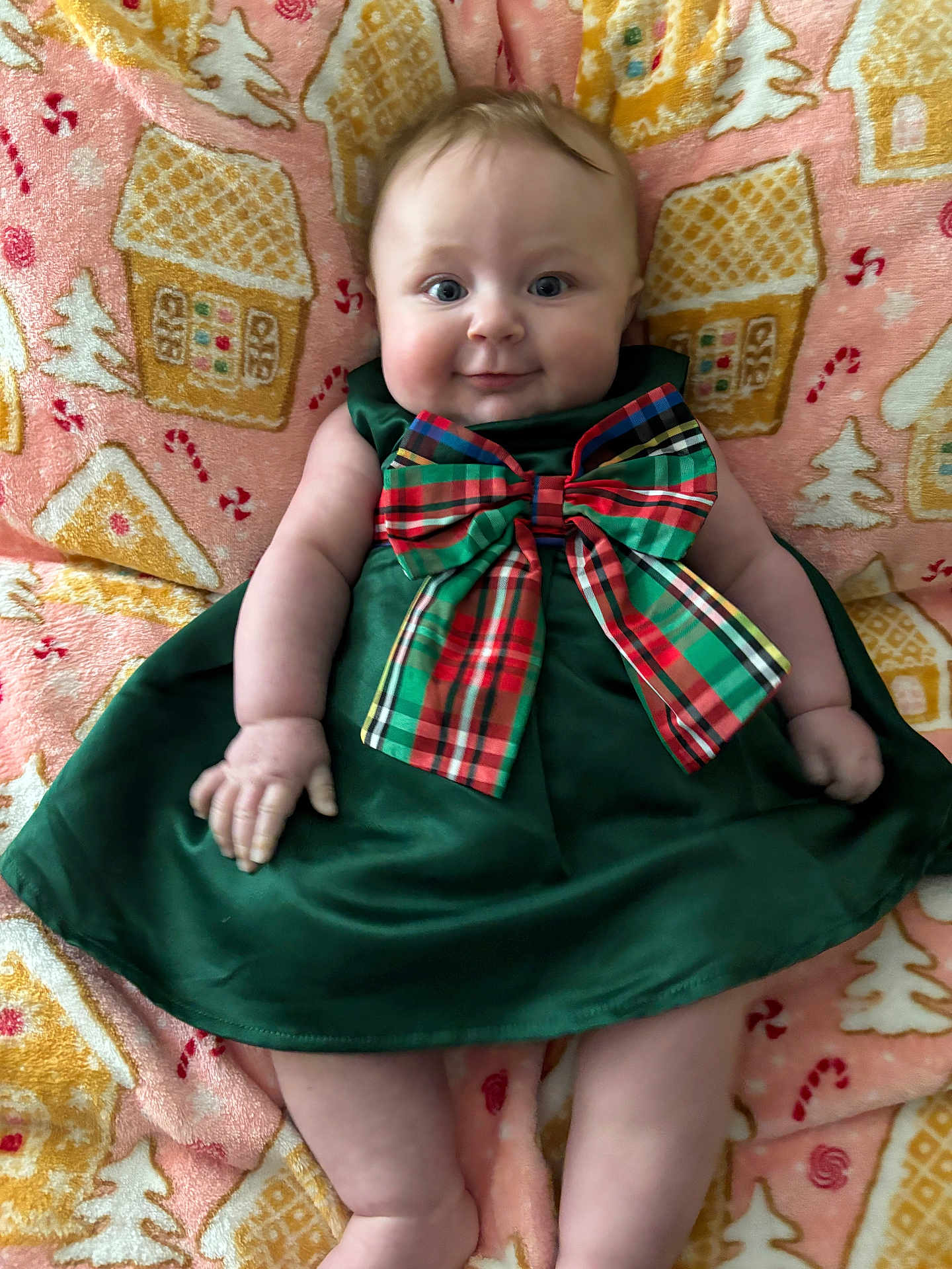 Amelia joined the competition — help win amazing prizes! baby, child, infant, dress, bow, plaid, green, holiday, blanket, pattern, gingerbread_house, candy_cane, smile, cute, chubby, lying_down, indoors, festive, cozy, portrait