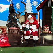 Amelia is registered to the contest to win money with this photo: baby, santa_claus, christmas, holiday, tree, reindeer, presents, chair, smile, decoration, festive, costume, portrait, indoor, celebration, white_beard, red_suit, child, seasonal, happy