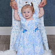 Amelia joined the competition — help win amazing prizes! baby, child, dress, blue_and_white, holding_hands, adult, floor, rug, hair_bow, pigtails, smiling, indoor, portrait, person, standing, happy, cute, flooring, patterned_clothing, family