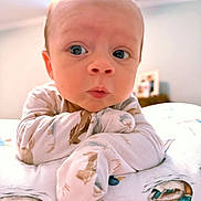 Waylon is registered to the contest to win money with this photo: baby, infant, face, pajamas, bed, curious, wide_eyes, soft_lighting, ceiling_fan, indoors, child, cute, expression, closeup, portrait, lying_down, animal_print, blanket, room, skin
