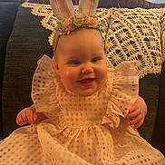 Tatum is registered to the contest to win money with this photo: baby, bunny_ears, child, clothing, couch, cute, doily, dress, fabric, feet, happy, headband, home, indoors, infant, lace, person, portrait, sitting, smile