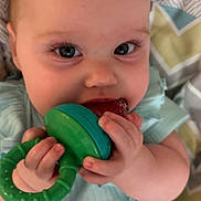 Tatum joined the competition — help win amazing prizes! baby, infant, teething_toy, green_toy, close_up, cute, child, face, hands, blue_clothing, seatbelt, patterned_blanket, indoor, young_child, chewing, holding, human, portrait, baby_seat, soft_lighting