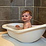 baby, bathtub, bathroom, child, water, wet_hair, smile, happy, tile_wall, white_tub, sitting, cute, indoor, water_droplets, playful, skin, head, face, person, bath_time