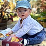 toddler, child, hat, bear_ears, potato_chips, snack, outdoor, garden, tiles, sitting, curious, blue_eyes, white_shirt, navy_pants, shoes, daylight, nature, greenery, portrait, baby