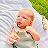 Colton joined the competition — help win amazing prizes! baby, infant, blanket, grass, outdoor, milestone_marker, wooden_marker, tongue_out, clothing, person, cute, newborn, hand, face, head, soft_texture, greenery, playful, one_month, portrait