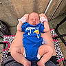 baby, newborn, sleeping, blue_onesie, mittens, pacifier, person, legs, outdoor, chair, patterned_fabric, concrete_wall, feet, hands, infant, relaxing, casual, skin, resting, closeup