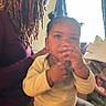 Saniyah is registered to the contest to win money with this photo: adult, baby, child, clothing, curious, curtains, dreadlocks, expression, face, furniture, hair, hand, indoor, light, person, pigtails, portrait, room, sitting, window