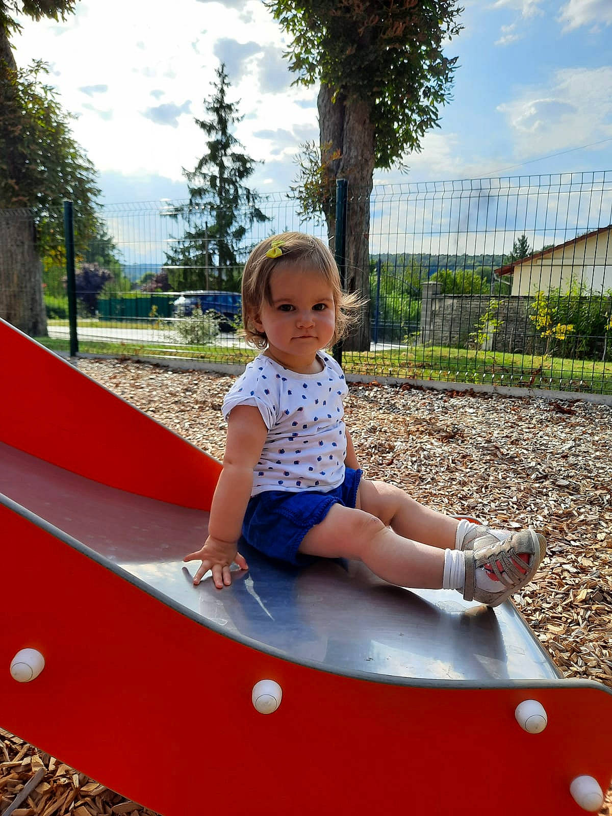 Emma a rejoint le concours — aidez-le/la à gagner de superbes lots ! child, city, cloud, electric_blue, fun, grass, happy, leg, leisure, outdoor_play_equipment, people_in_nature, person, plant, recreation, shorts, sky, summer, t_shirt, thigh, toddler