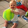 baby_toys, ball, blond_hair, child, cute, floor, footwear, happy, indoor, play, shorts, sitting, smile, tile_floor, toddler, toy, tshirt, walker, white_shoes, wooden_cabinet
