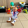 baby, ball, child, clothing, colorful, floor, happy, indoor, person, plastic_toys, playing, sitting, smiling, soccer_ball, socks, sportswear, tiles, toddler, toys, white_shoes