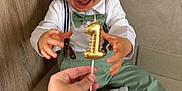 Lewen participe au concours pour gagner de l'argent avec cette photo : birthday, bow_tie, boy, candle, celebration, child, cute, green_pants, hand, happy, indoor, number_one, party, person, portrait, smiling, suspenders, tile_floor, toddler, white_shoes