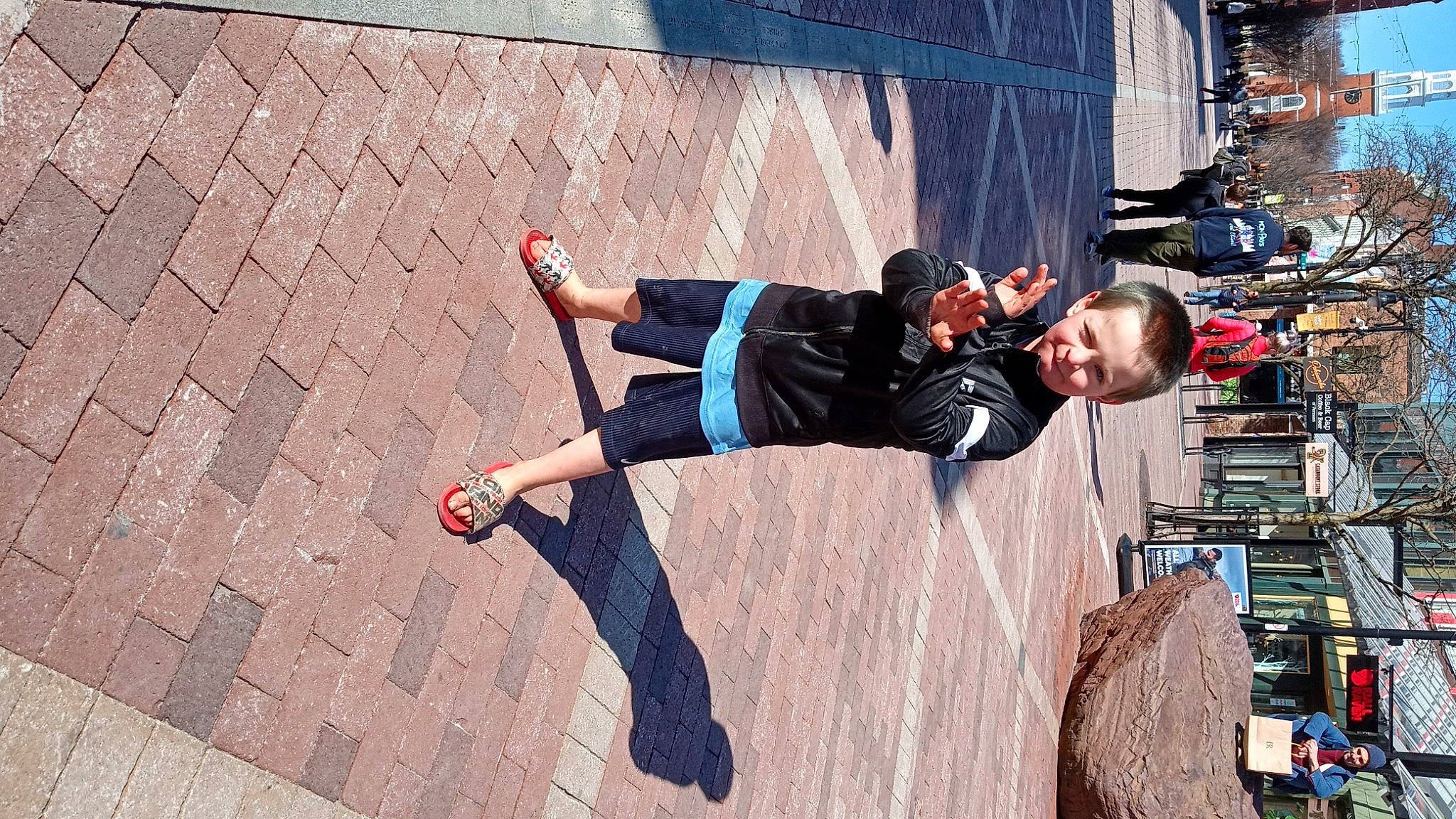 Colton is registered to the contest to win money with this photo: city, denim, electric_blue, eyewear, fun, headwear, human_leg, joy, knee, leisure, pattern, pedestrian, person, recreation, road, shadow, shorts, sidewalk, sportswear, street