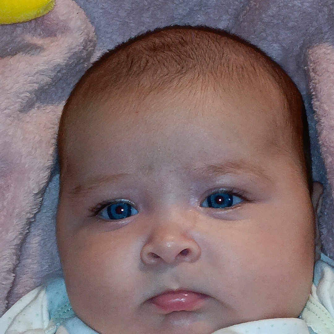 Maya joined the competition — help win amazing prizes! baby, bed, blanket, bodypart, bonnet, clothing, crib, face, frown, furniture, hat, head, homedecor, infantbed, mouth, newborn, person, photography, portrait, towel