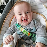 Oscar is registered to the contest to win money with this photo: baby, baby_seat, child, closeup, clothing, comfort, cushion, cute, expression, face, hand, happy, indoor, infant, joy, onesie, pacifier_clip, person, smiling, soft_toy