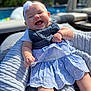 Desiree is registered to the contest to win money with this photo: baby, smiling, headband, blue_dress, striped_dress, knitted_blanket, outdoor, sunlight, happy, infant, portrait, closeup, child, cute, relaxing, summer, poolside, person, skin, cheerful
