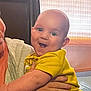 baby, child, smile, yellow_shirt, indoor, adult_hand, curtain, happy, person, face, arm, holding, joy, light, casual_clothing, infant, expression, cute, human, portrait